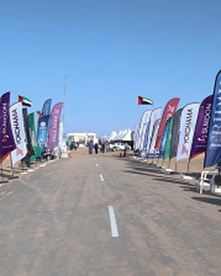 An event approach lined with sponsor flags and UAE flags on a clear desert day
