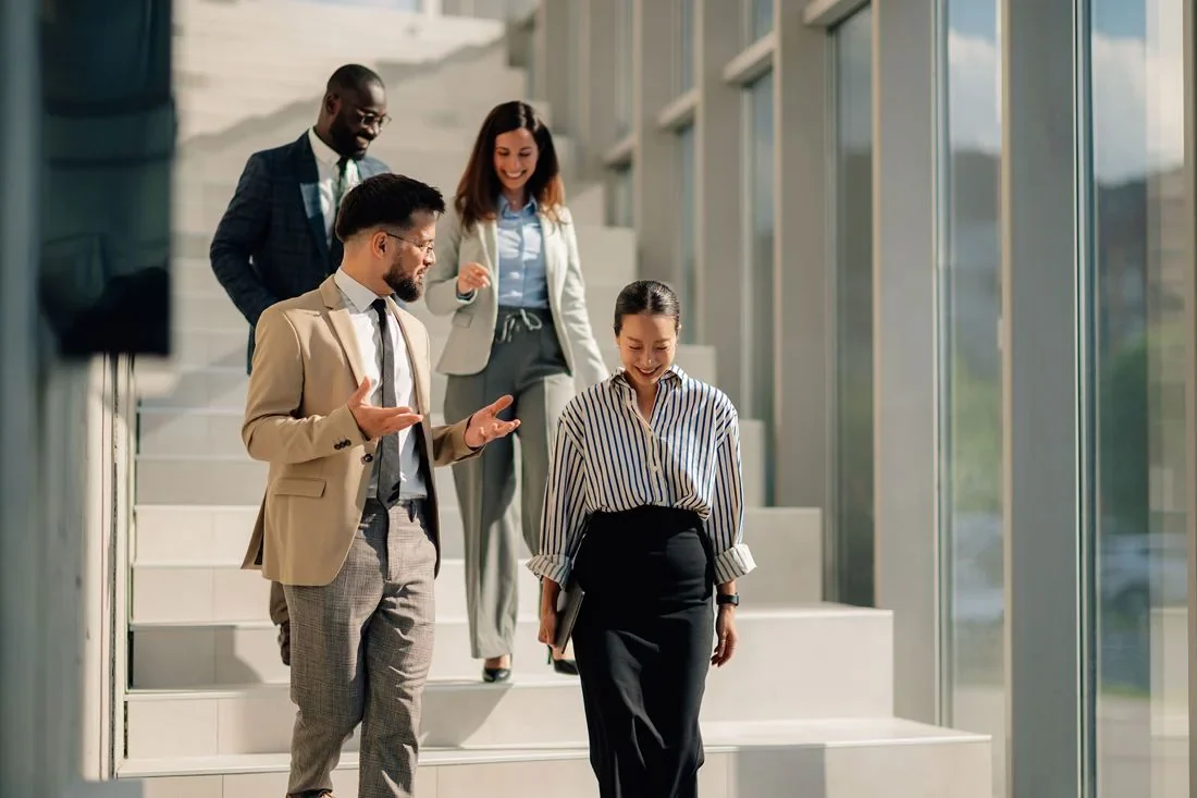 A diverse team of colleagues talking as they walk down office stairs